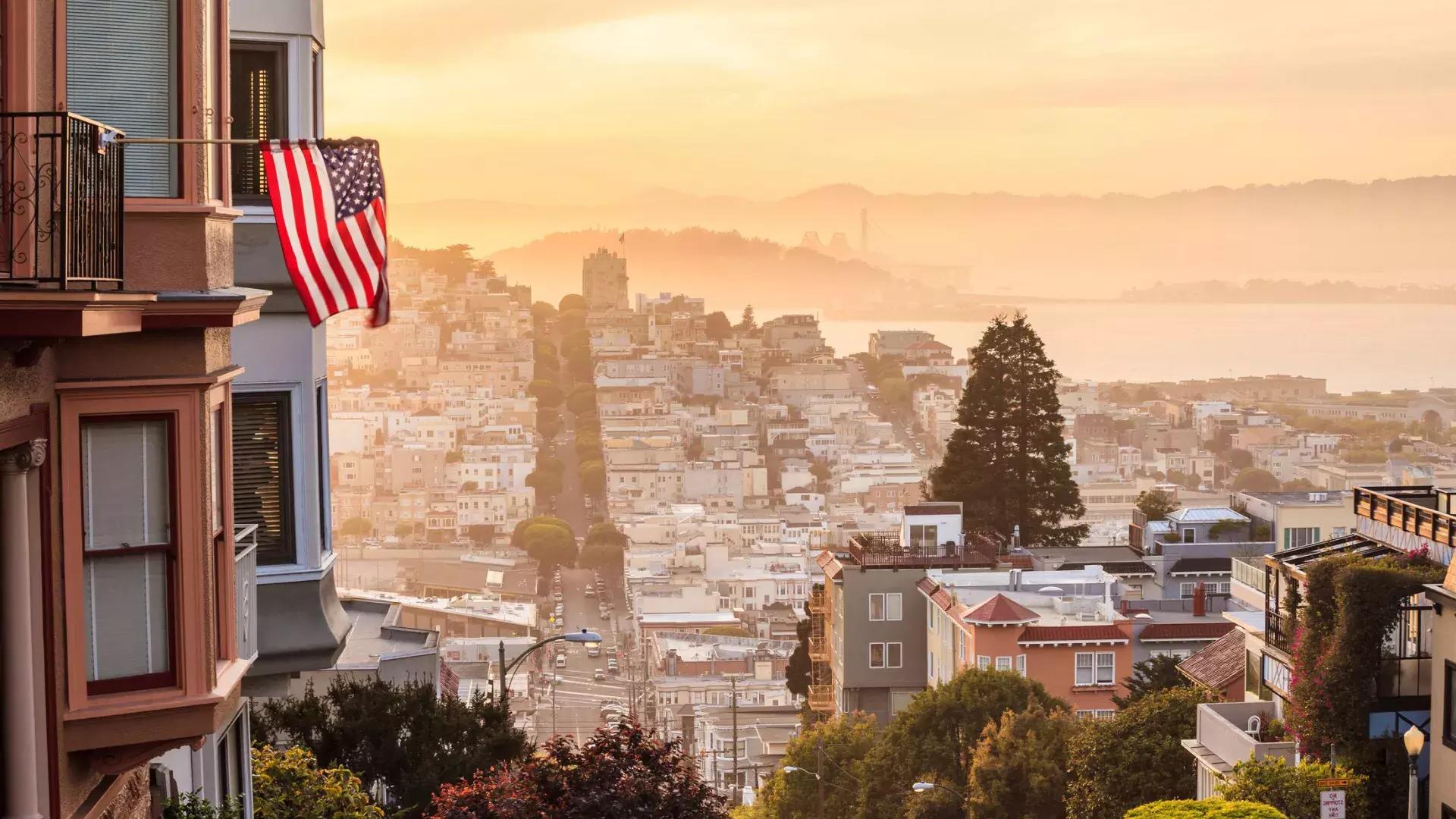 从山顶俯瞰贝博体彩app的景色, 前景是一面飘扬的美国国旗.