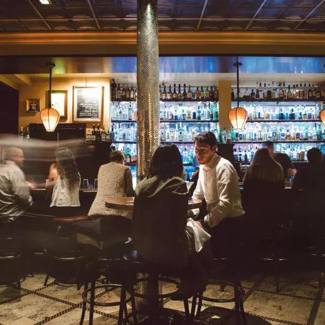 A couple share drinks at a busy San Francisco bar.